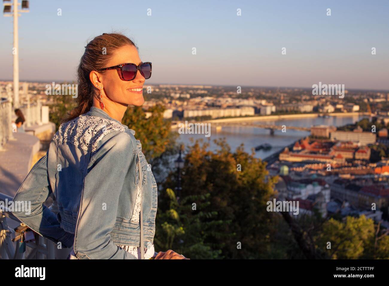 Young urban woman wondering in city panorama, orange sunset Stock Photo