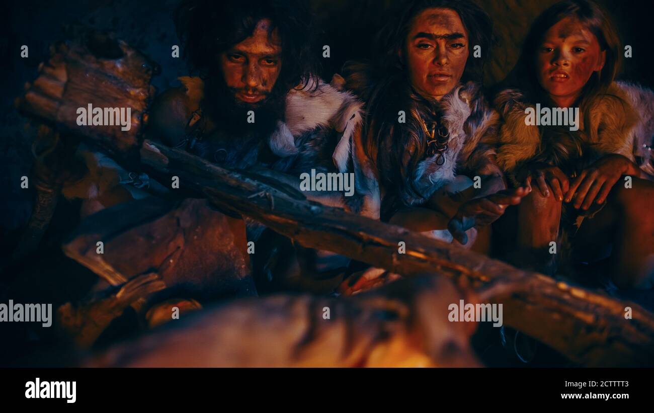 Neanderthal or Homo Sapiens Family Cooking Animal Meat over Bonfire and