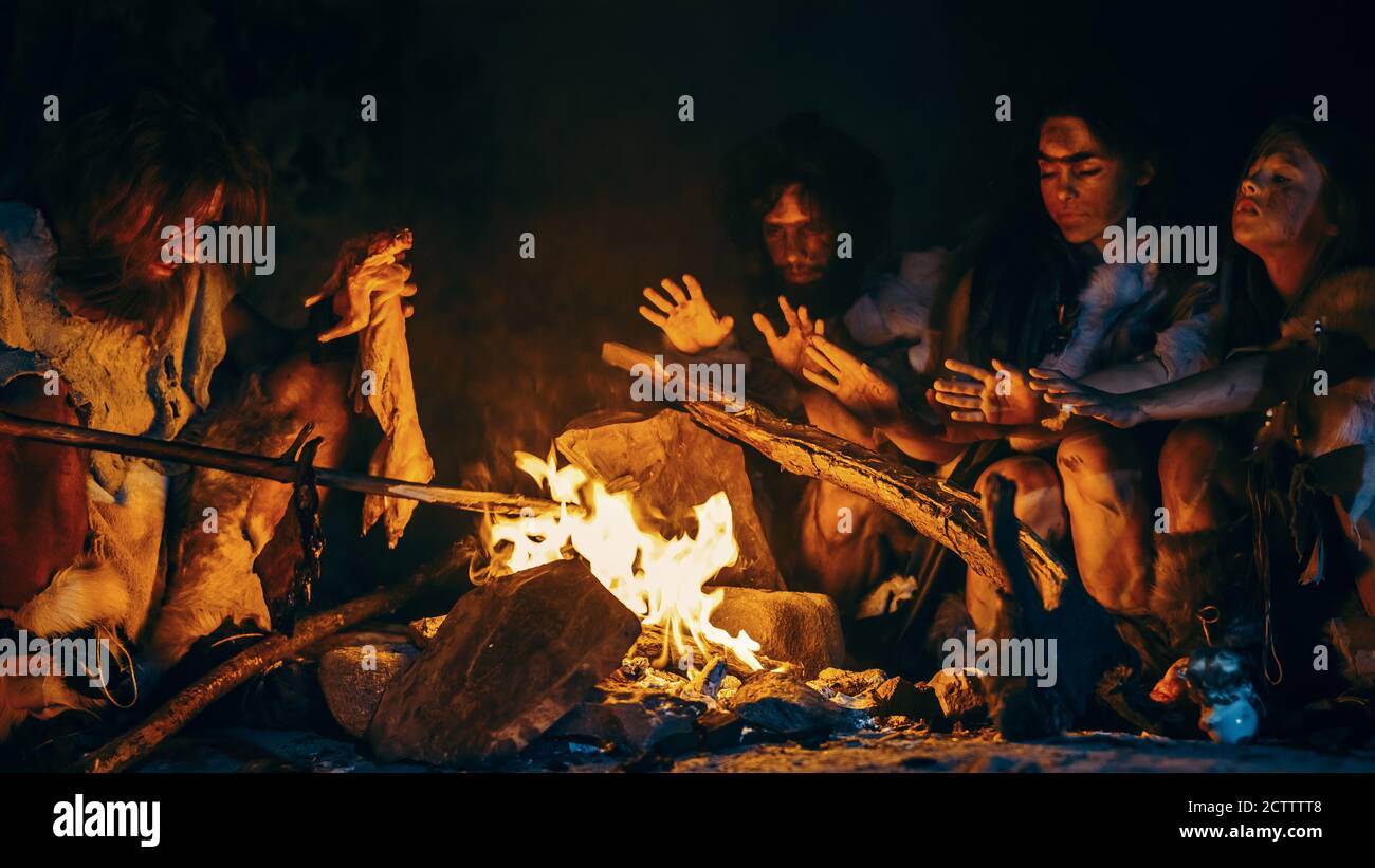 Neanderthal or Homo Sapiens Family Cooking Animal Meat over Bonfire and