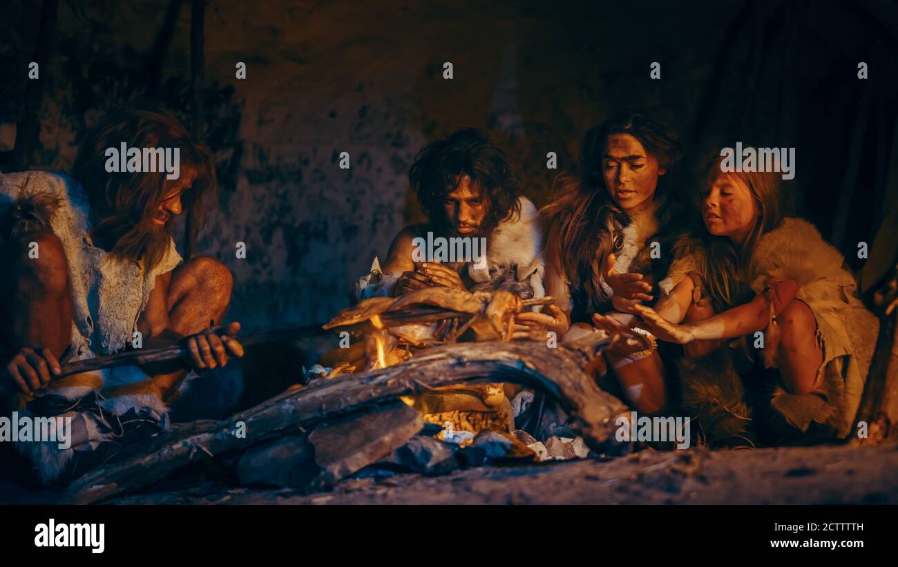 Neanderthal or Homo Sapiens Family Cooking Animal Meat over Bonfire and