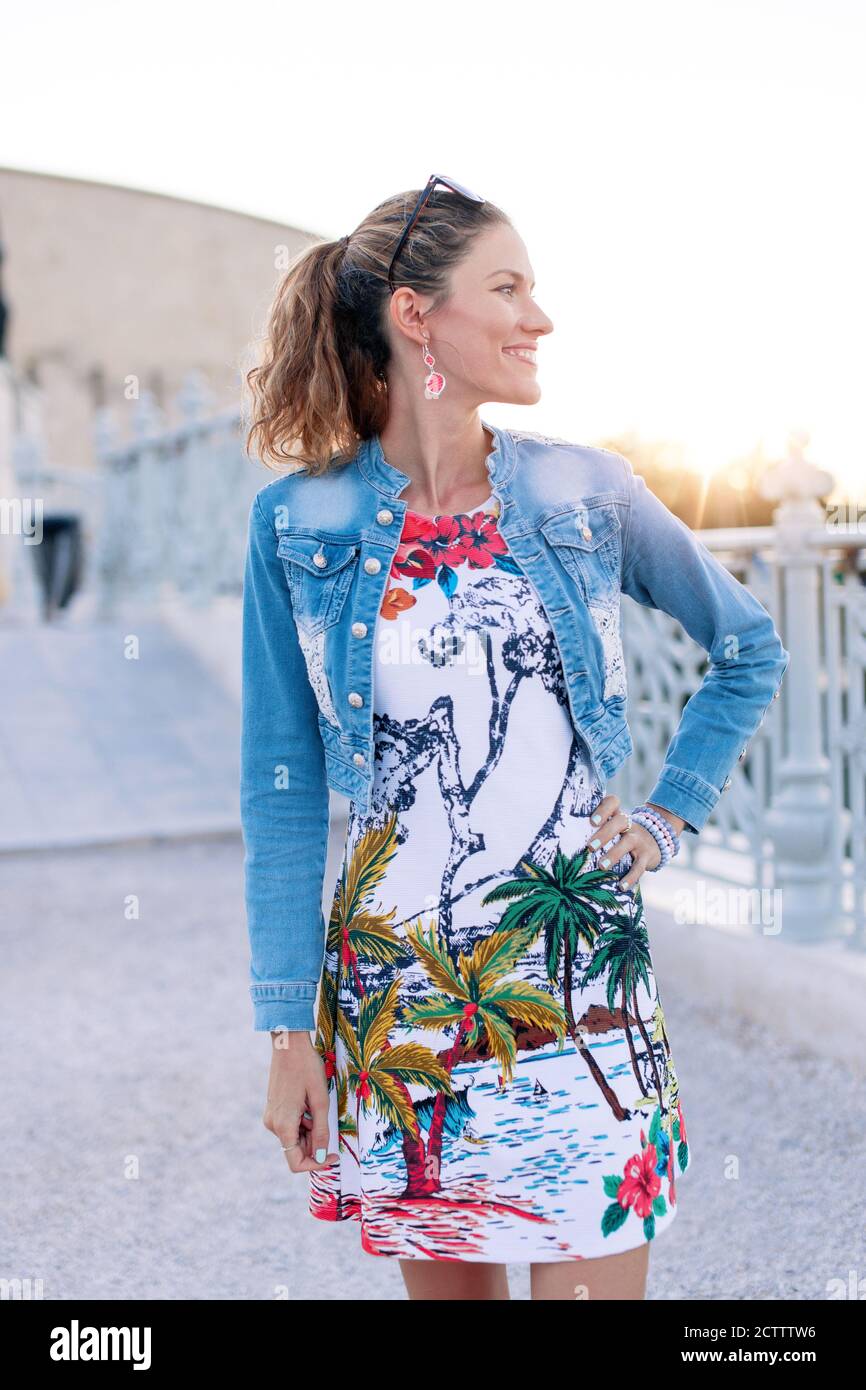 Happy young stylish urban woman posing outdoors in sunset Stock Photo