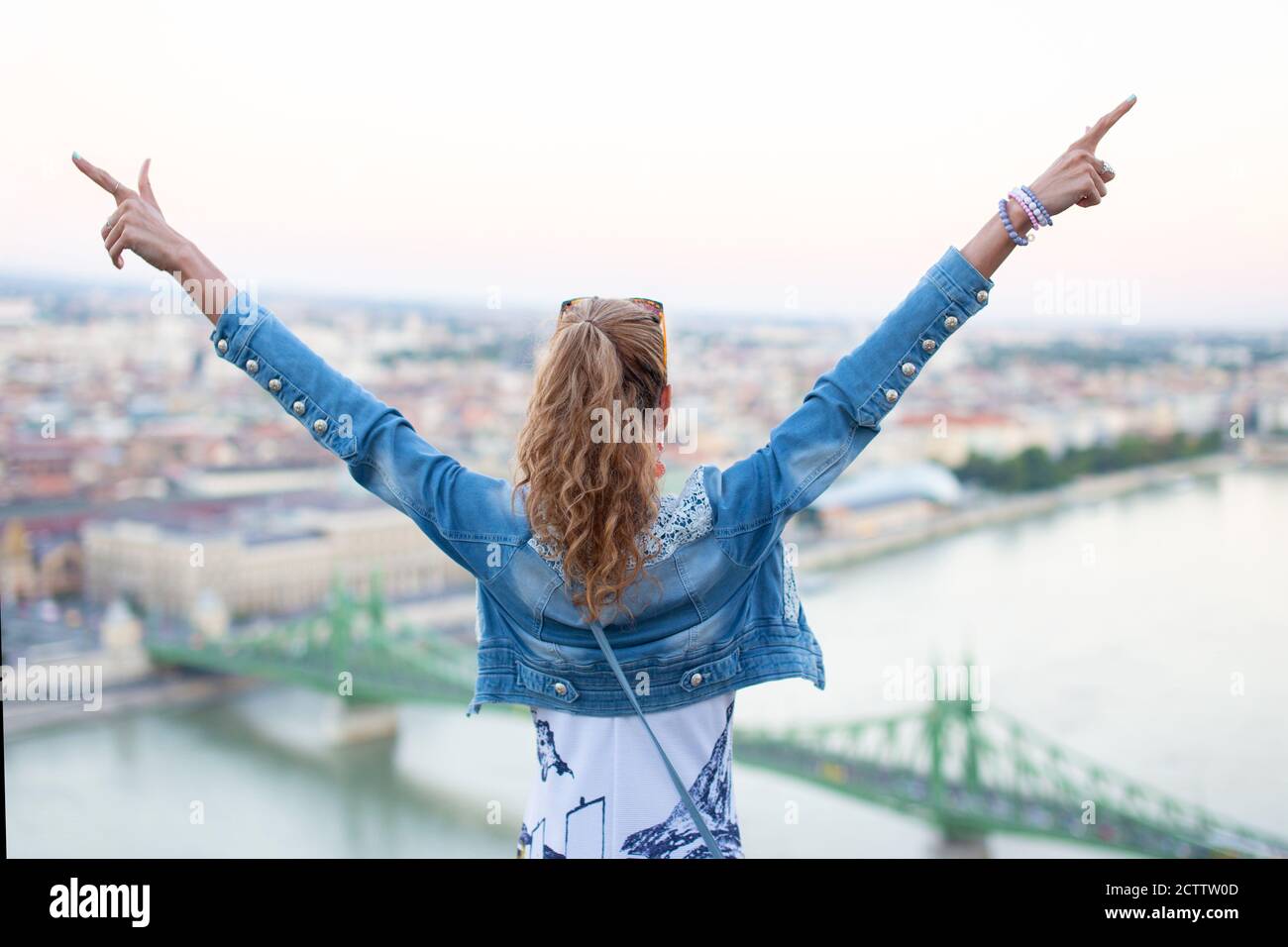 Young woman arms raised at Liberty Bridge, Budapest, Hungary Stock Photo