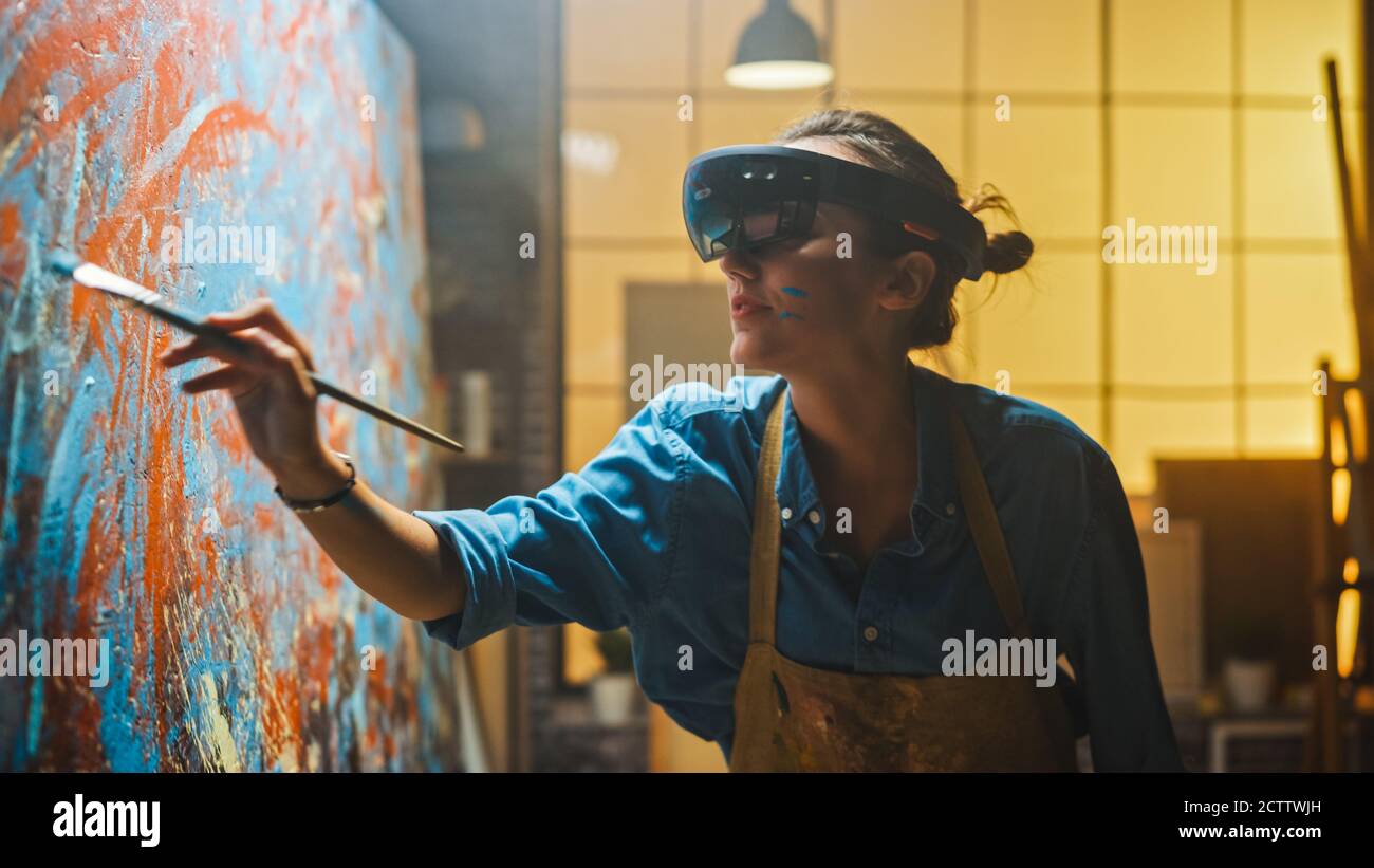 Talented Female Artist Wearing Augmented Reality Headset Working on Abstract Painting, Uses Paint Brush To Create New Concept Art Using Virtual Stock Photo