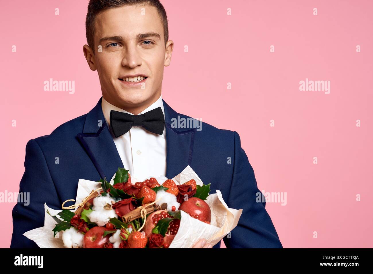 Handsome man in a classic suit with a bouquet of flowers on a pink ...