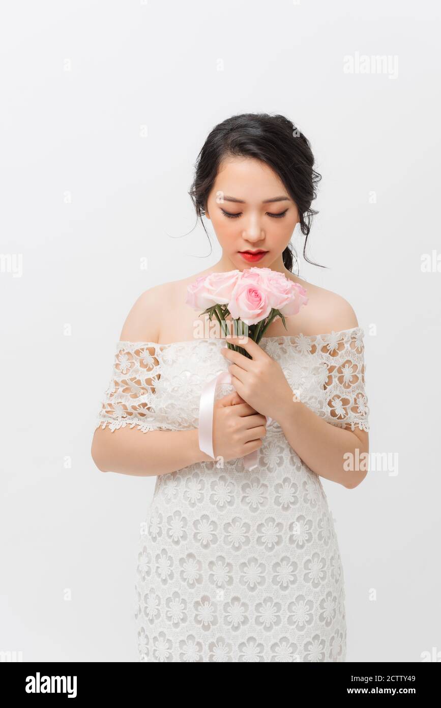 Profile portrait of a beautiful young woman smelling pink rose and ...