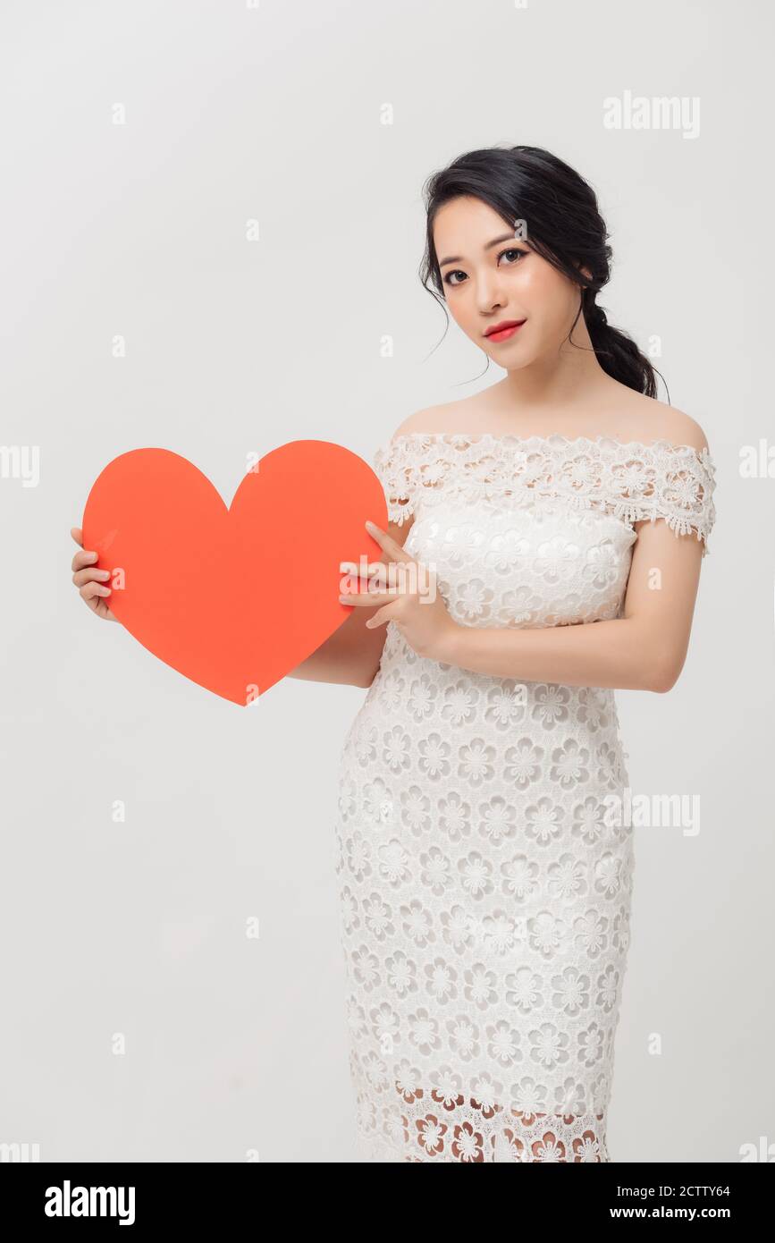 Happy young Asian holding love shape while standing isolated over white ...