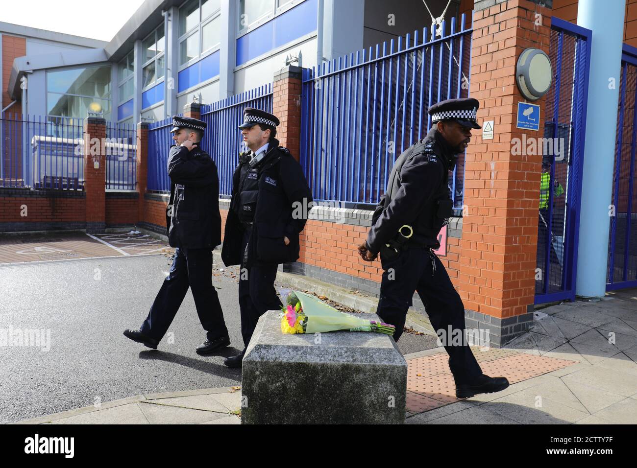 Police officers walk past flowers left outside Croydon Custody Centre in south London where a police officer was shot by a man who was being detained in the early hours of Friday morning. The officer was treated at the scene before being taken to hospital where he subsequently died. Stock Photo