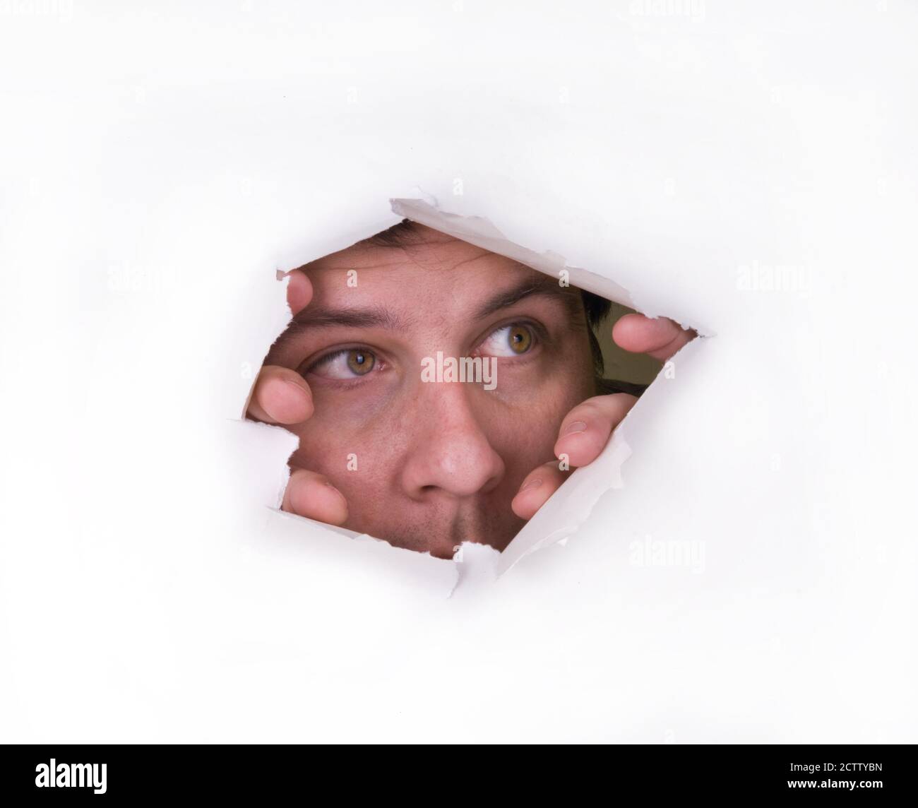 A man looks through a hole in the paper Stock Photo