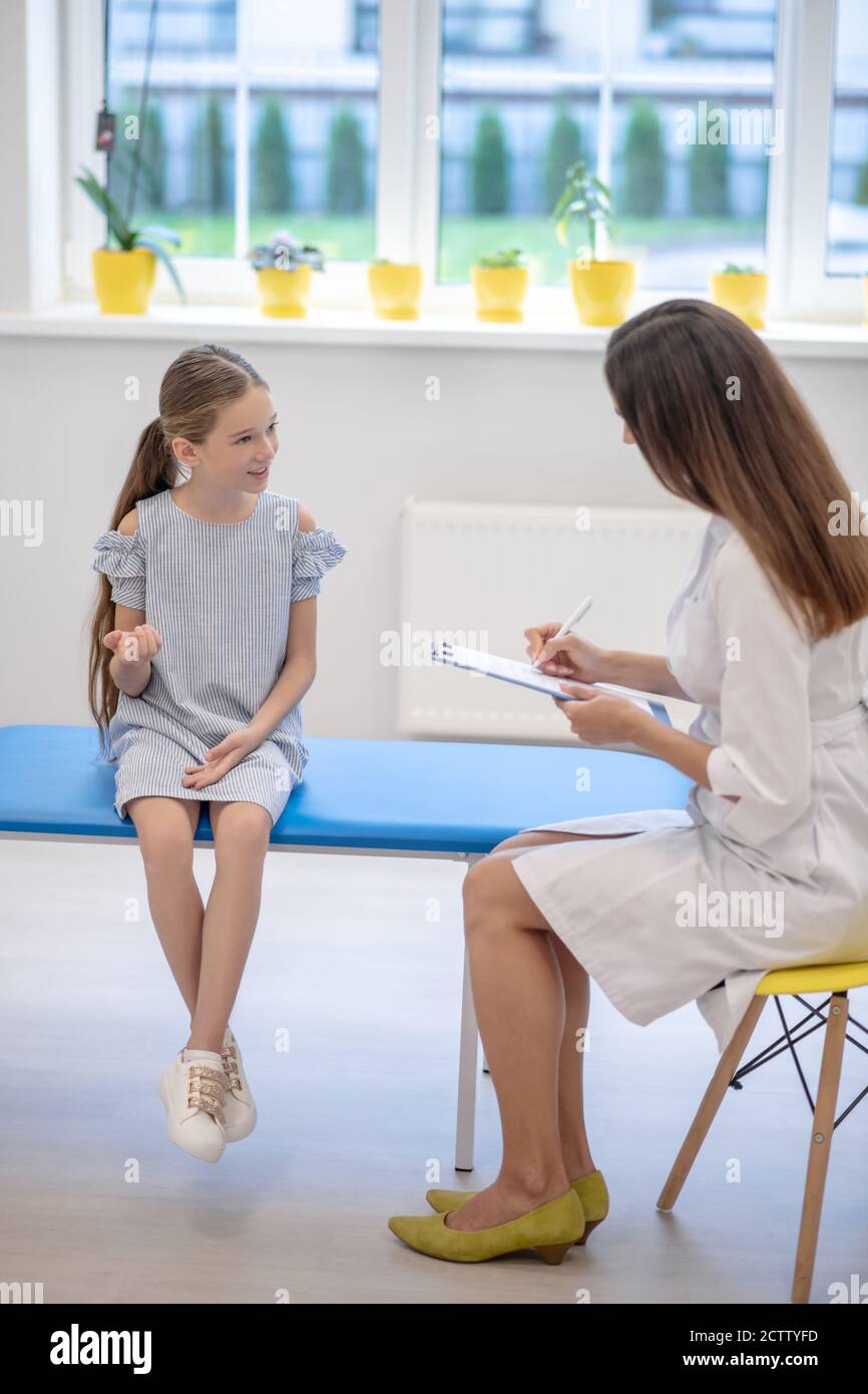 Girl sitting on a couch and talking to the female doctor Stock Photo ...