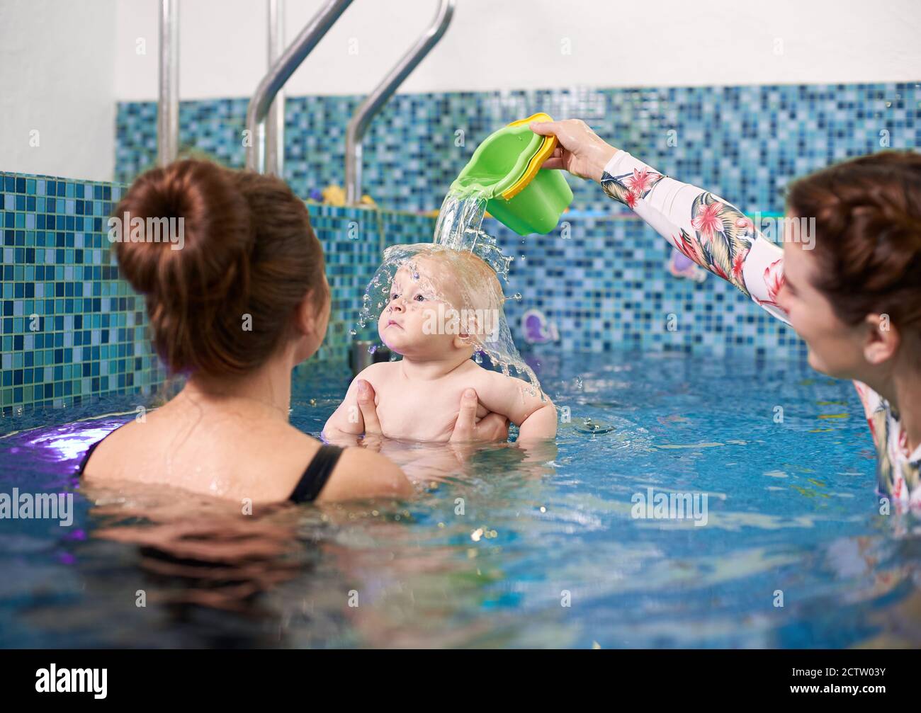 Image of swimming lesson for infants. Young mother holding her little