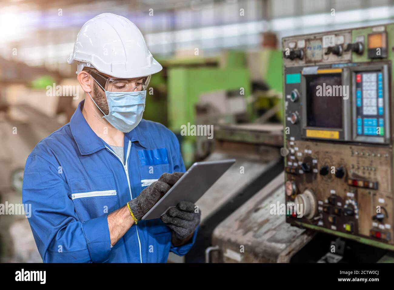 Worker wearing face shield or disposable face mask during working service in factory to prevent Coronavirus(Covid-19) or air dust pollution in factory Stock Photo
