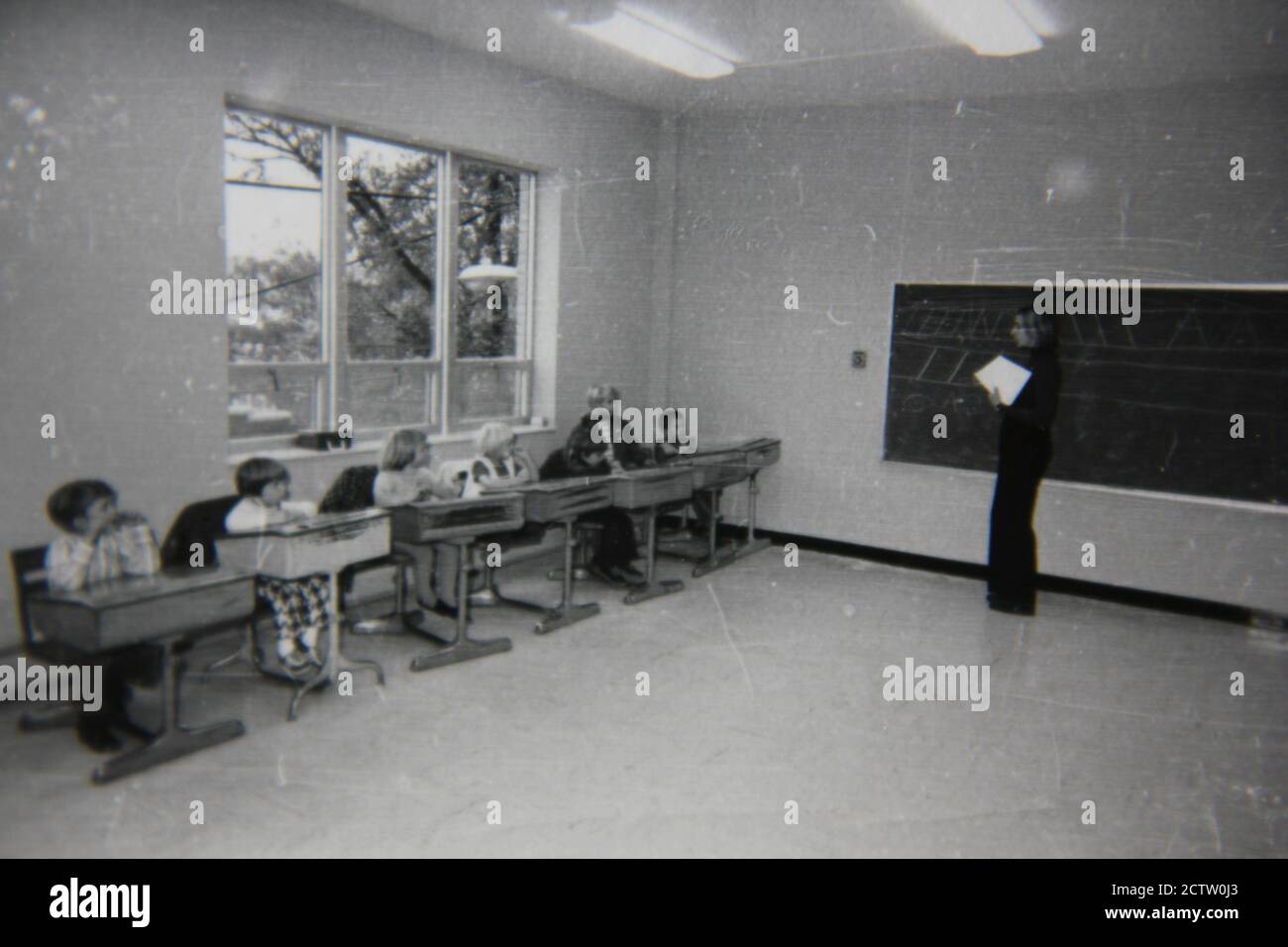 Fine 1970s vintage black and white photography of elementary school students siting in their classroom desks learning their lessons. Stock Photo