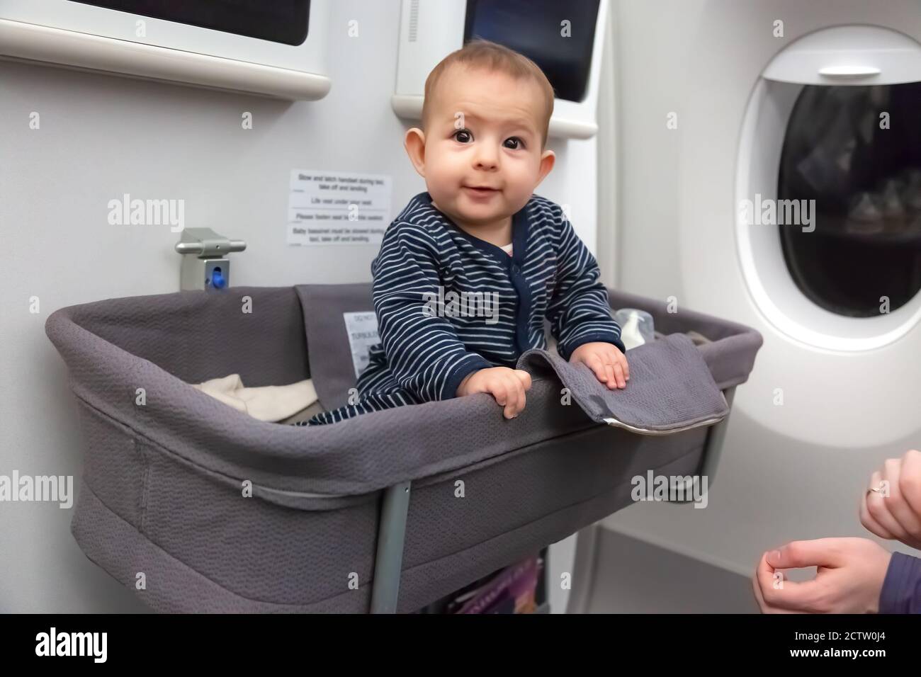 Infant girl sit in special baby bassinet in airplane. She is laugh and amazed, it is first flight Stock Photo - Alamy