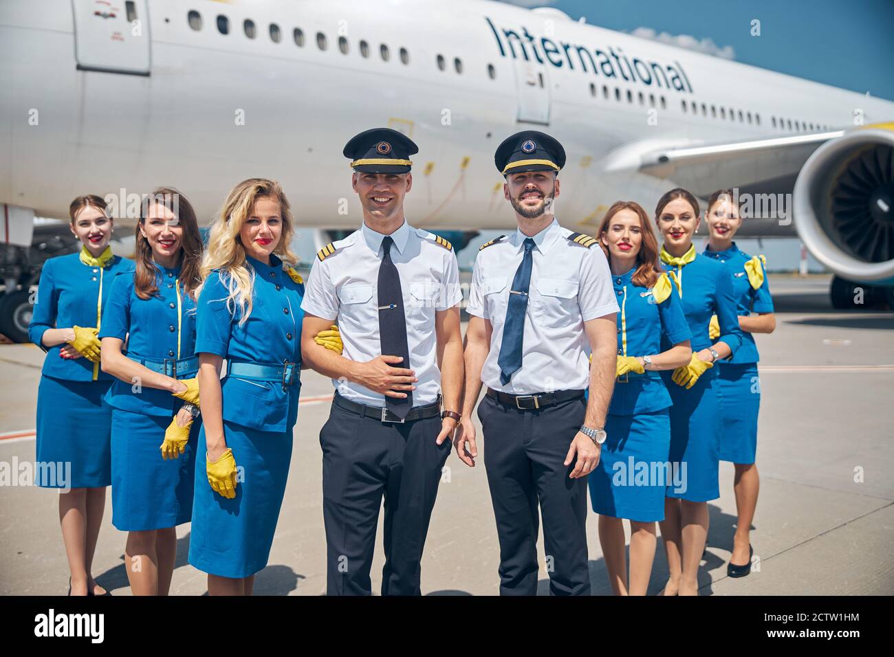 Cheerful airline workers or aircrew standing outdoors in airfield Stock Photo