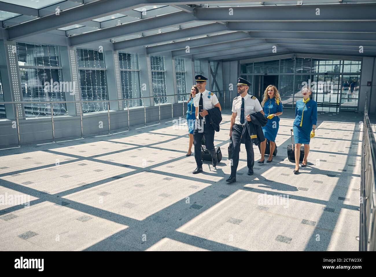 Airline workers with travel suitcases walking in airport terminal Stock Photo