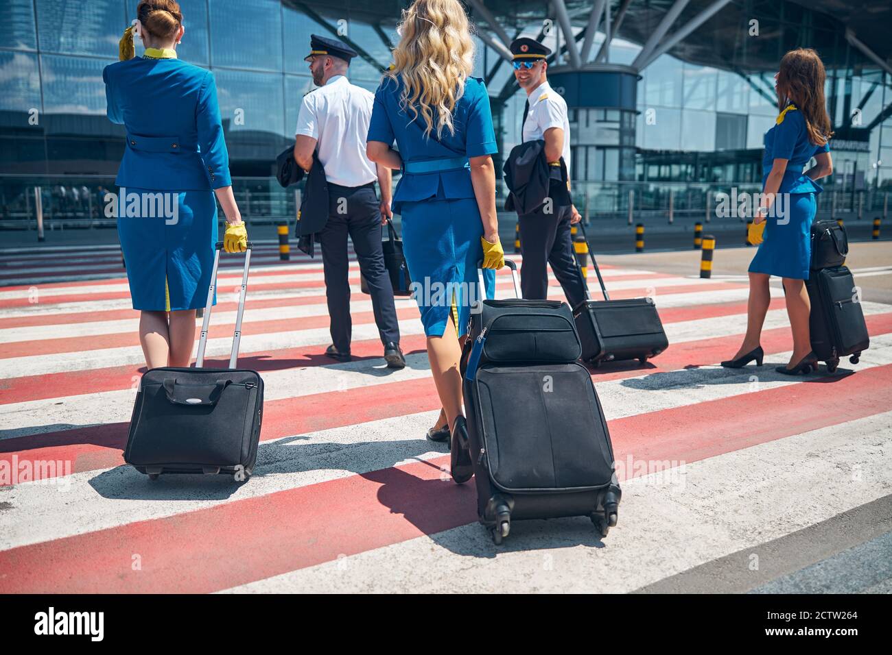 Aircrew with travel bags crossing the road at airport Stock Photo