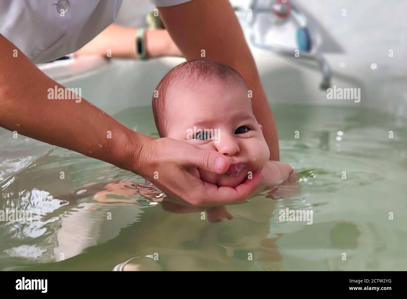 Infant baby in special pool with doctor instructor. Newborn children ...