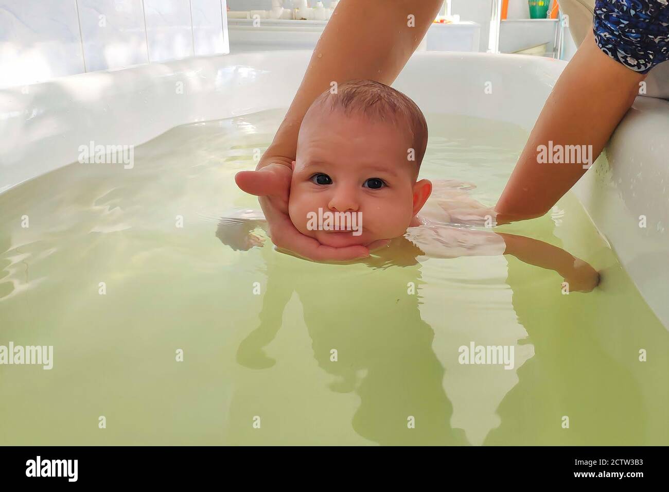 Infant baby in special pool with doctor instructor. Newborn children ...