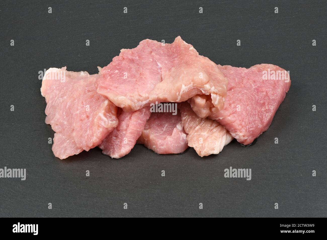 Fresh raw pork slice isolated on black slang stone. High resolution