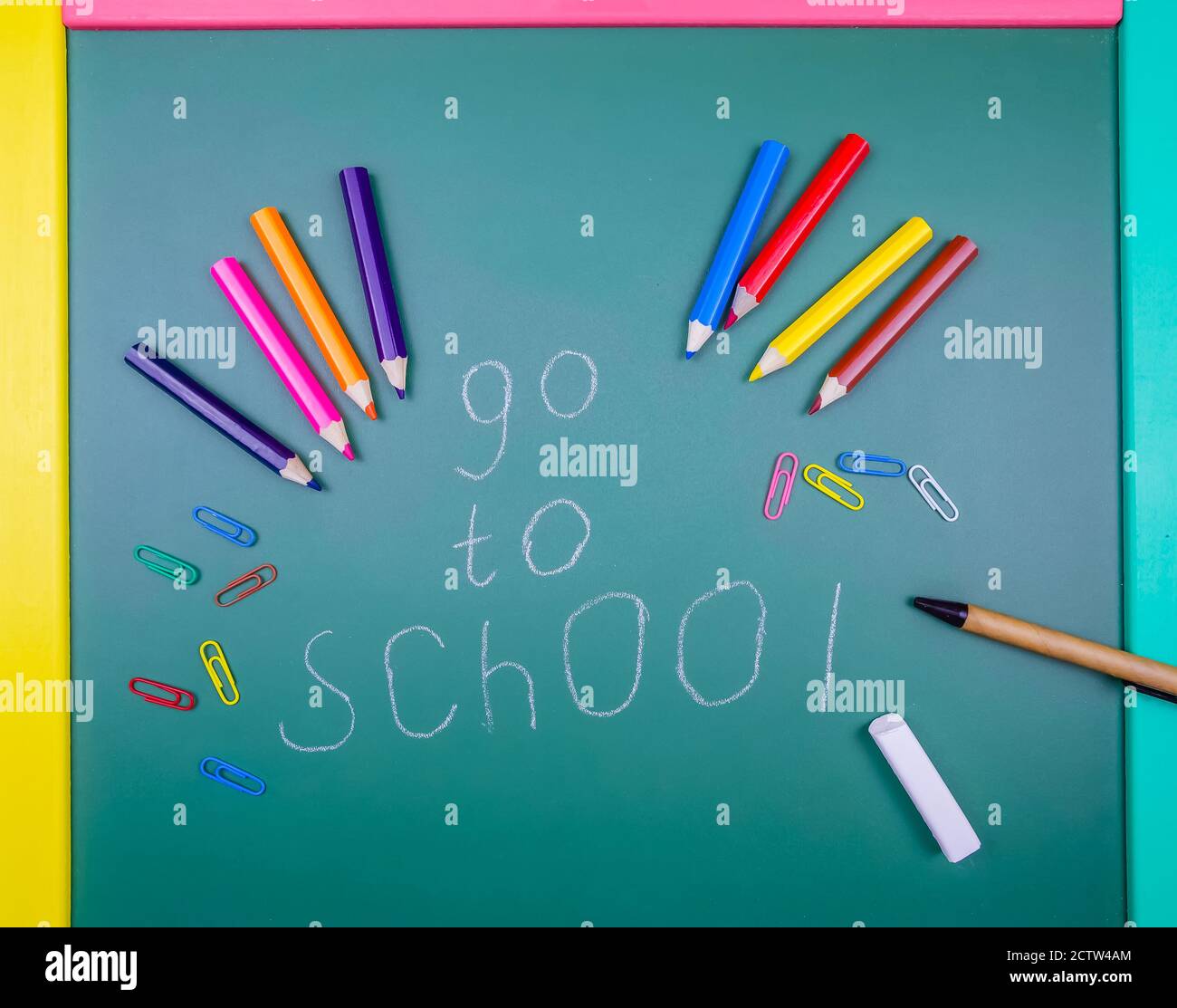 On a green Board Go to shool says pencils, colored paper clips, and a pen. School concept, academic year. Beautiful, fun background for school. Stock Photo