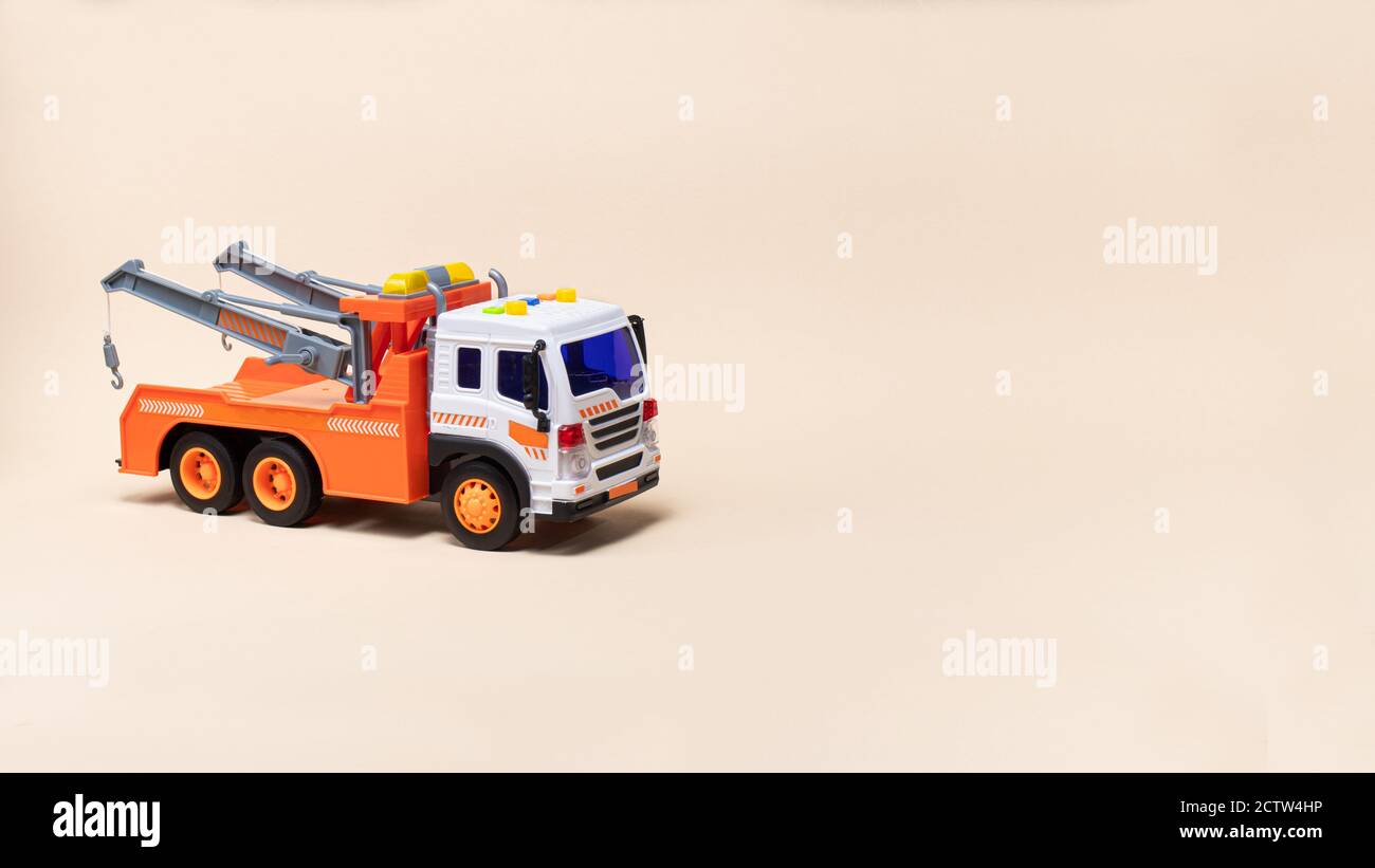 Toy orange tow truck on beige background banner with space for text. Children's car for loading and transporting cars Stock Photo