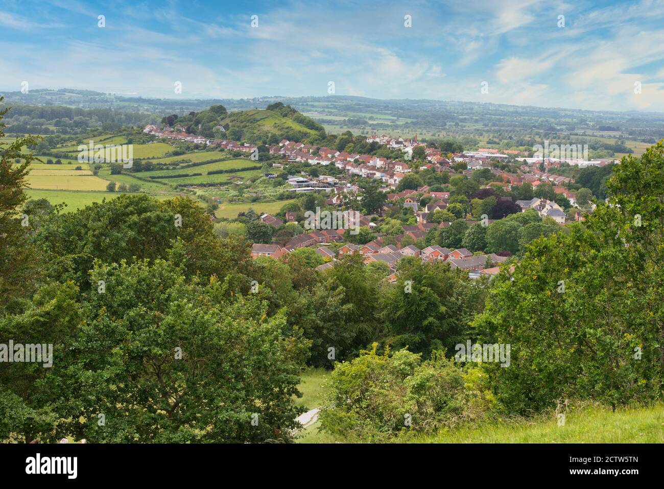 Overview of Glastonbury from the top of the Tor. Blue sky and white clouds. Pilgrimage site for New Age practitioners. Farmland and town. Stock Photo