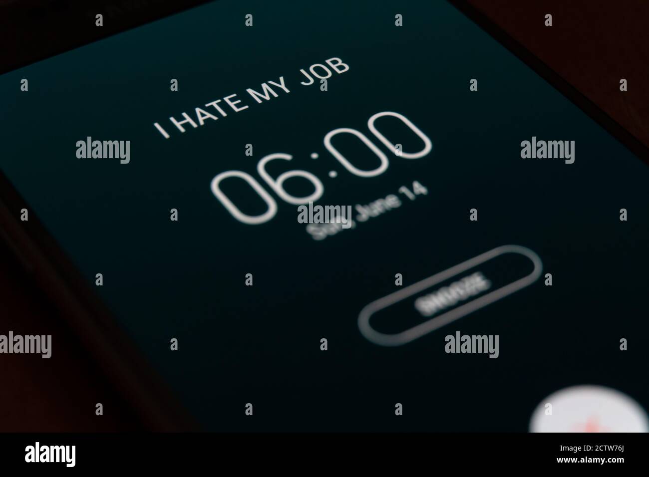 On a black smartphone, an alarm clock rings for 6 am with the inscription I hate my job close-up, background Stock Photo