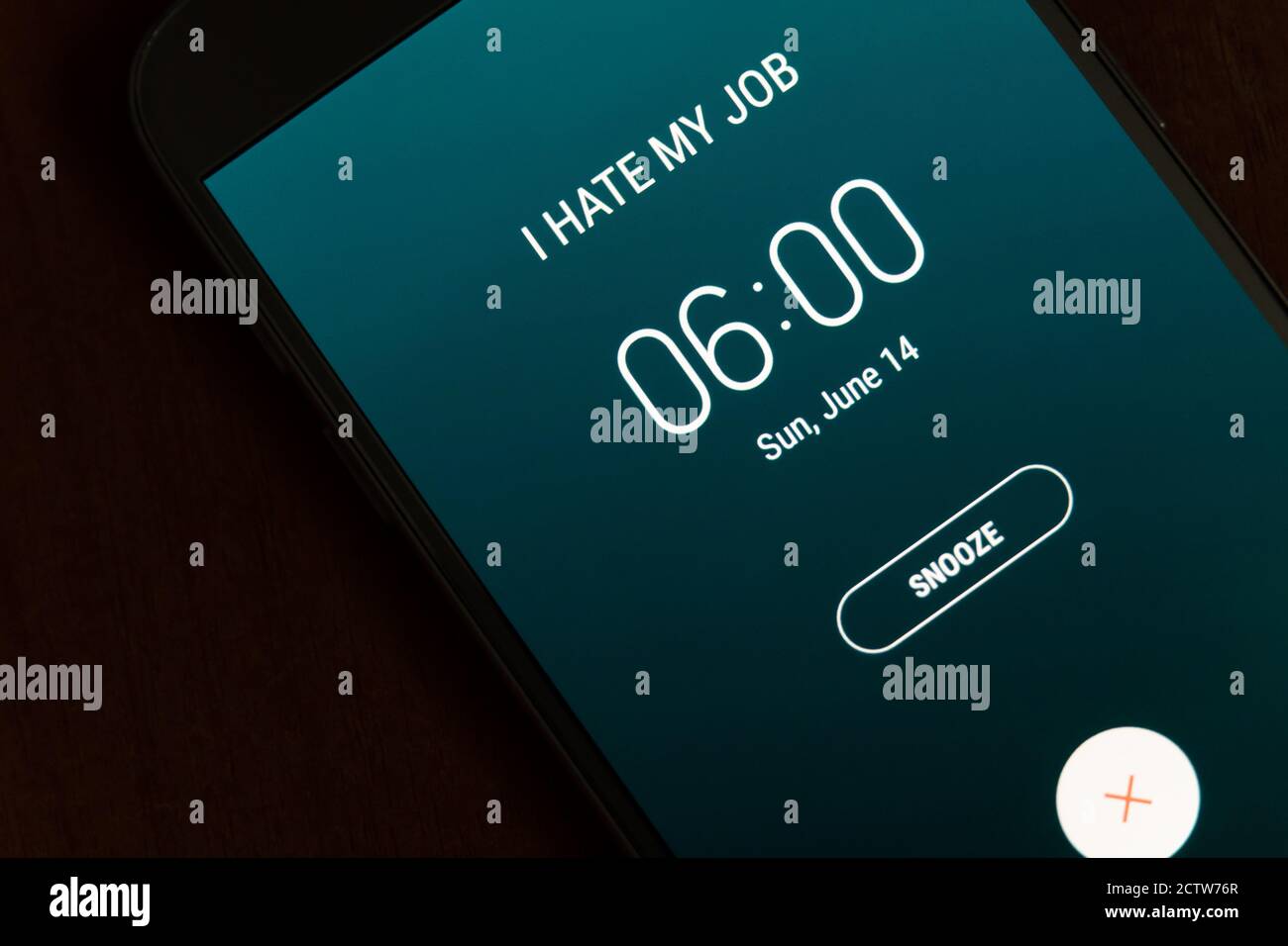 On a black smartphone, an alarm clock rings for 6 am with the inscription I hate my job close-up, background Stock Photo