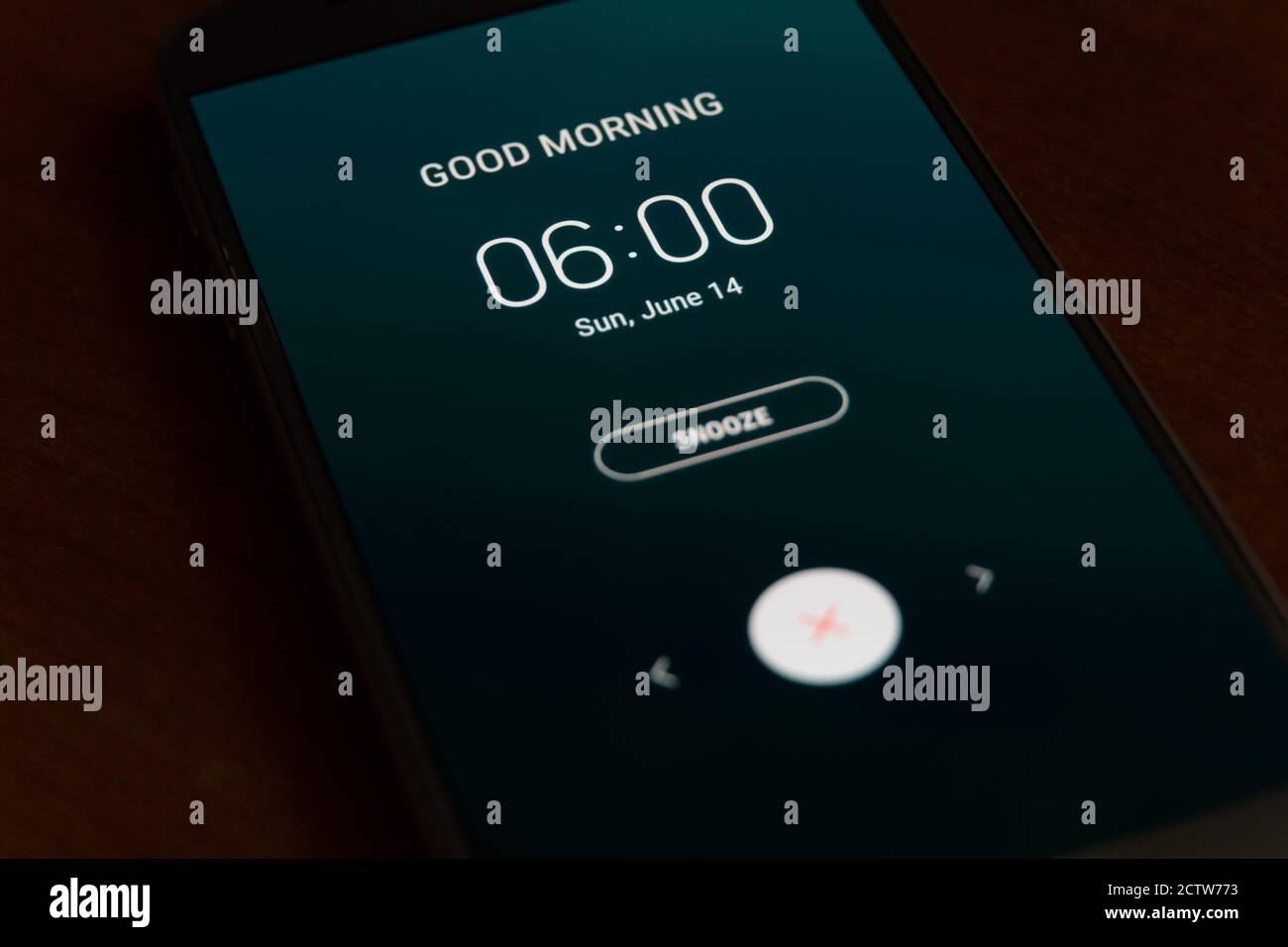 On a black smartphone, an alarm clock rings for 6 am with the