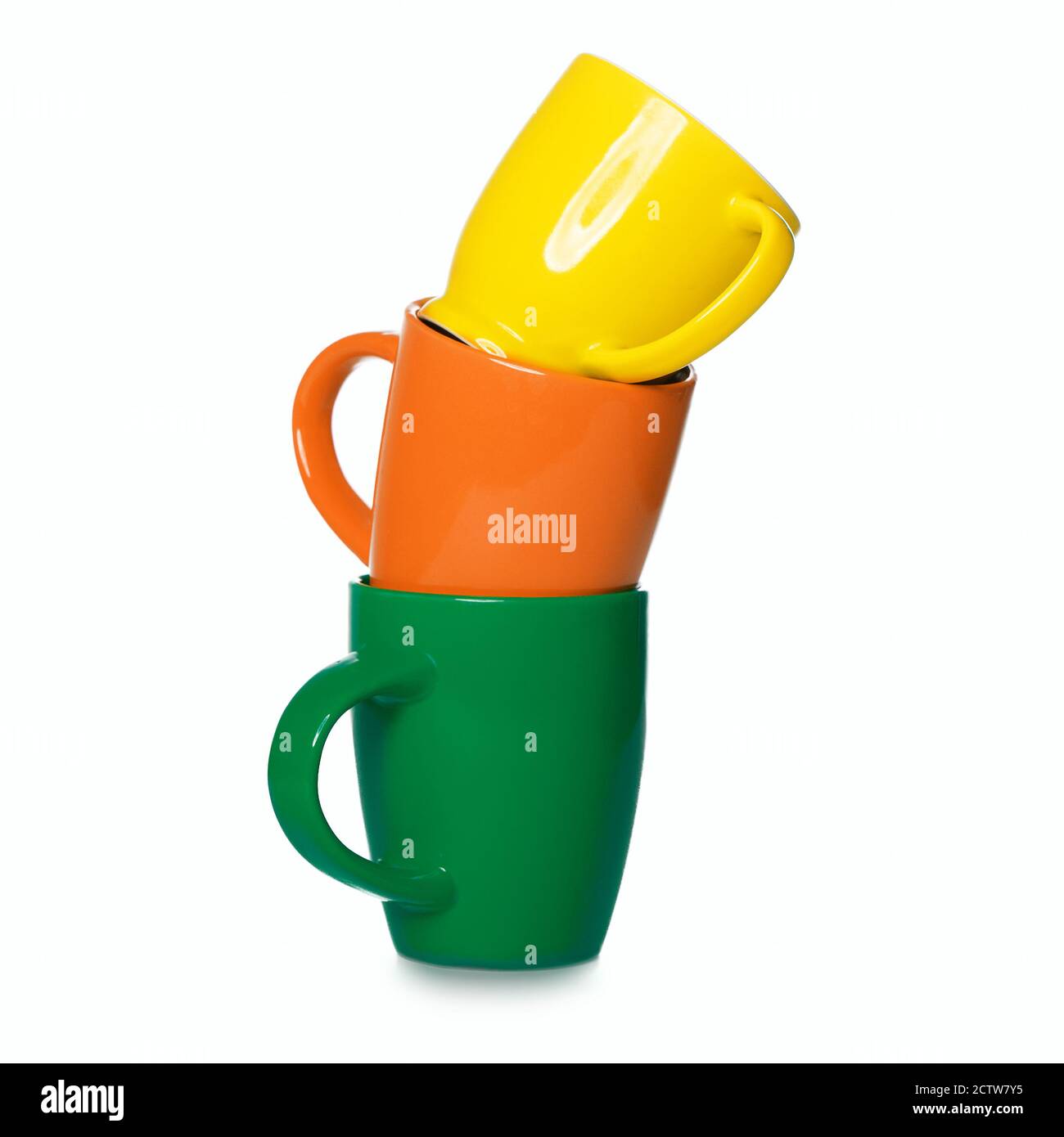 Stack of three motley cups isolated on white background. Three coffee mugs - orange, green and yellow Stock Photo