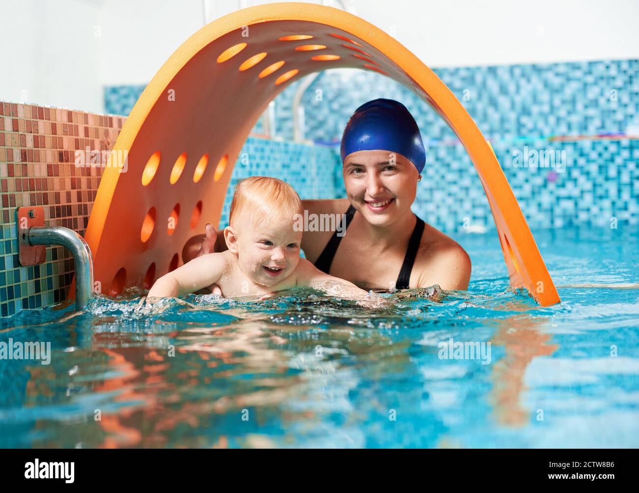 Interesting active training in swimming pool. Happy cute boy is learning how to float with his