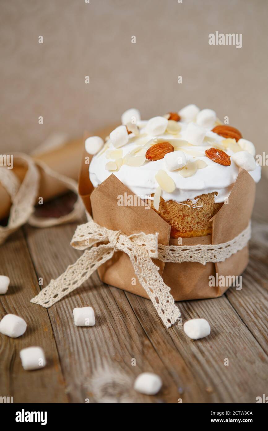 Easter composition. Easter cake decorated with almond petals and marshmallows on a rustic wooden background. Stock Photo