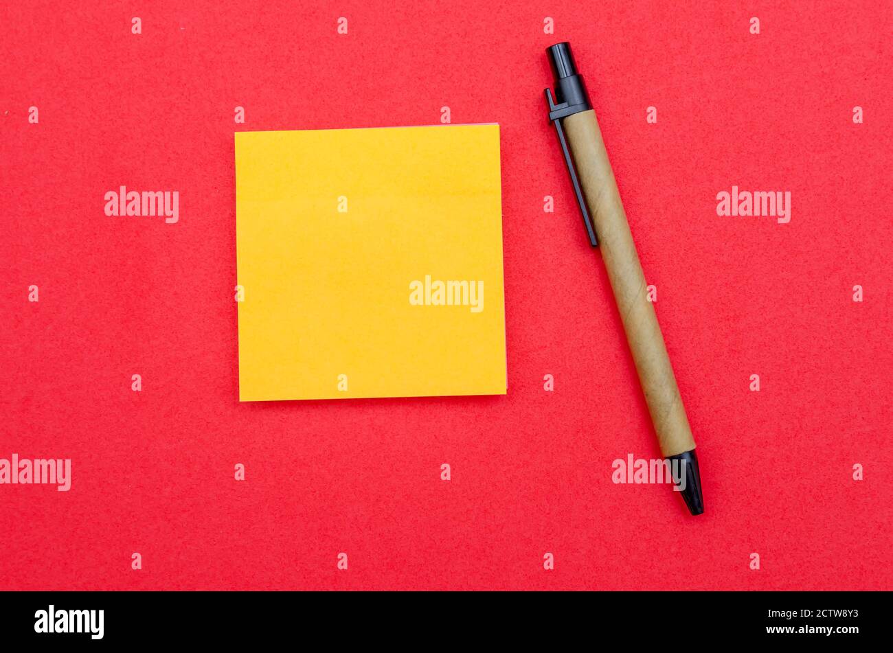 Yellow sheet of writing paper, ballpoint pen on red background, copy