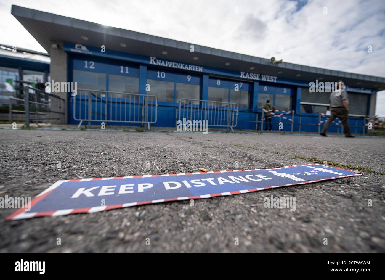 25 September 2020, North Rhine-Westphalia, Gelsenkirchen: A man is standing  at an open ticket office in front of the Veltins-Arena, the stadium of  Schalke 04, while on the floor there is a