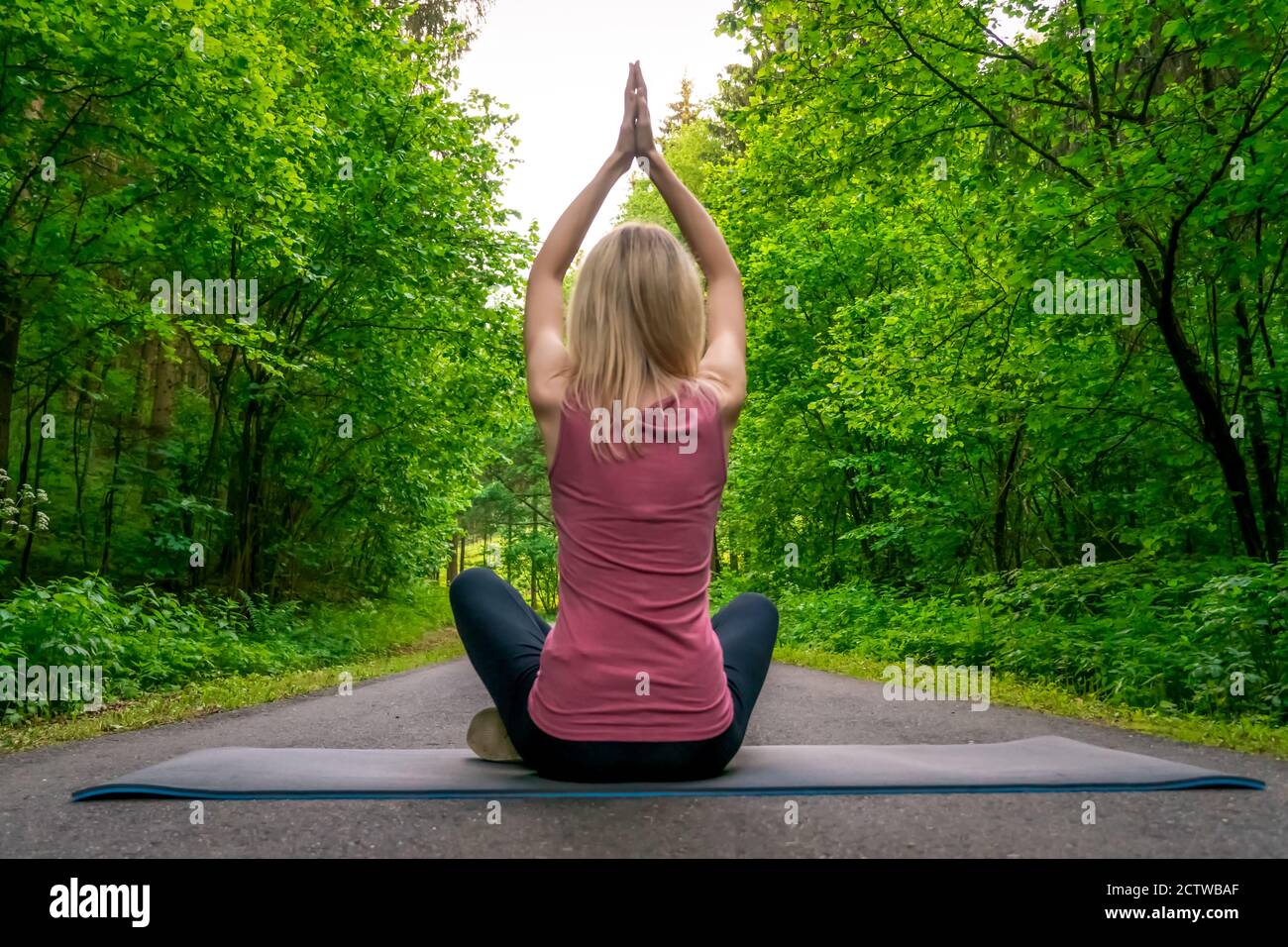 Young slim woman with blonde hair sitting on the yoga mat in split