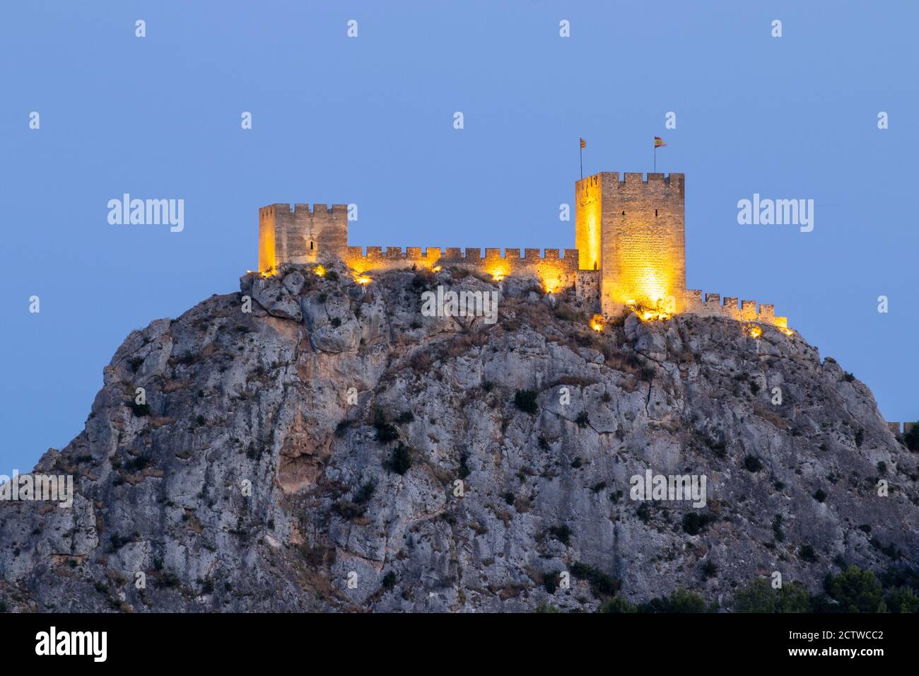 Castillo de Sax on rocks surrounded by lights in the evening in Spain Stock Photo
