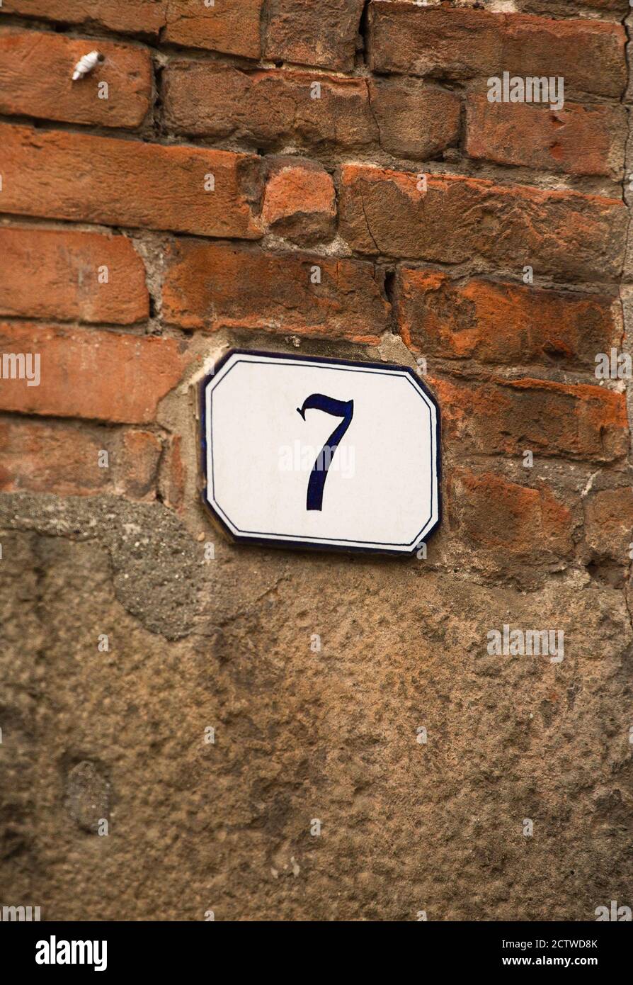 House number plaque on old brick wall. House number 7 on building. May 2013. Pisa, Italy. High quality photo Stock Photo