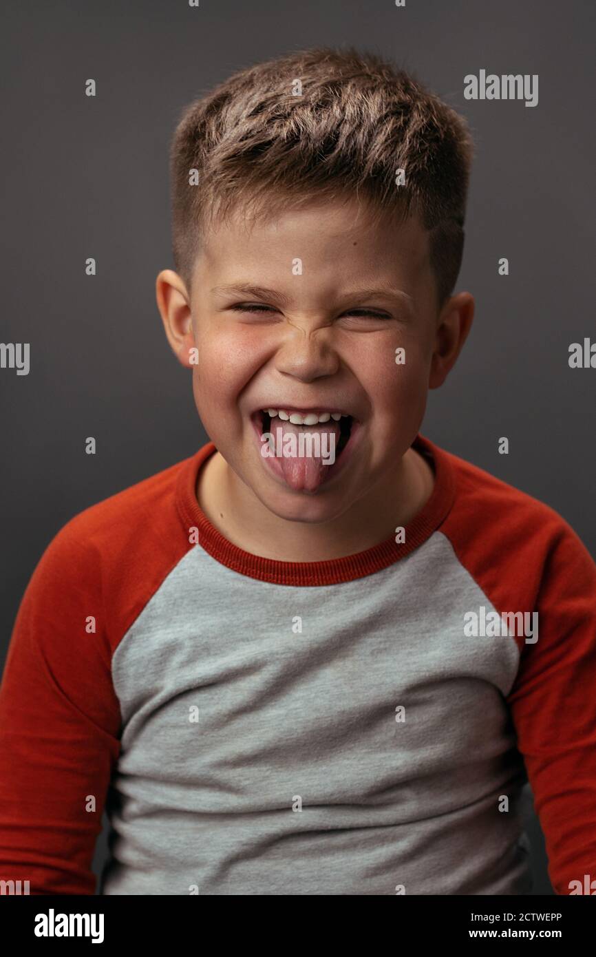 Adorable boy shows his tongue to the camera. Portrait of a funny boy in