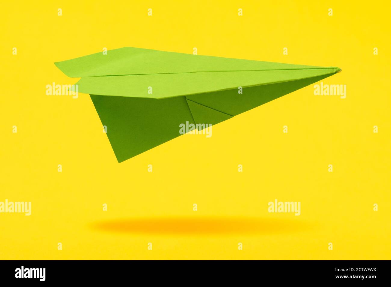 Green paper aircraft fly over yellow background Stock Photo Alamy