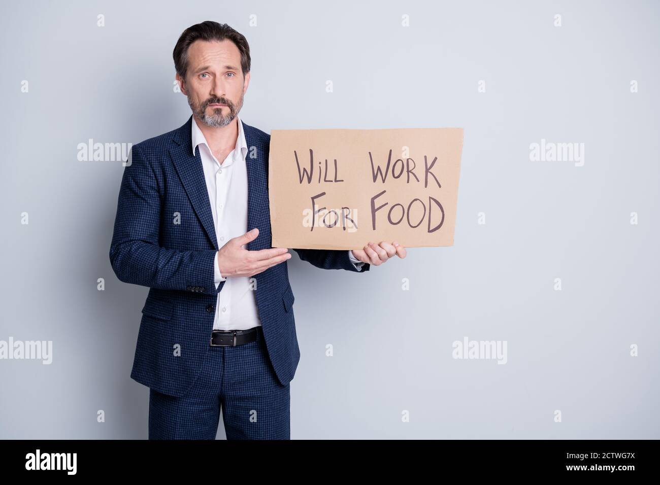 Photo of serious sad poor homeless workless dismissed guy suffer financial crisis lost work hold placard search work for some food exchange wear blue Stock Photo