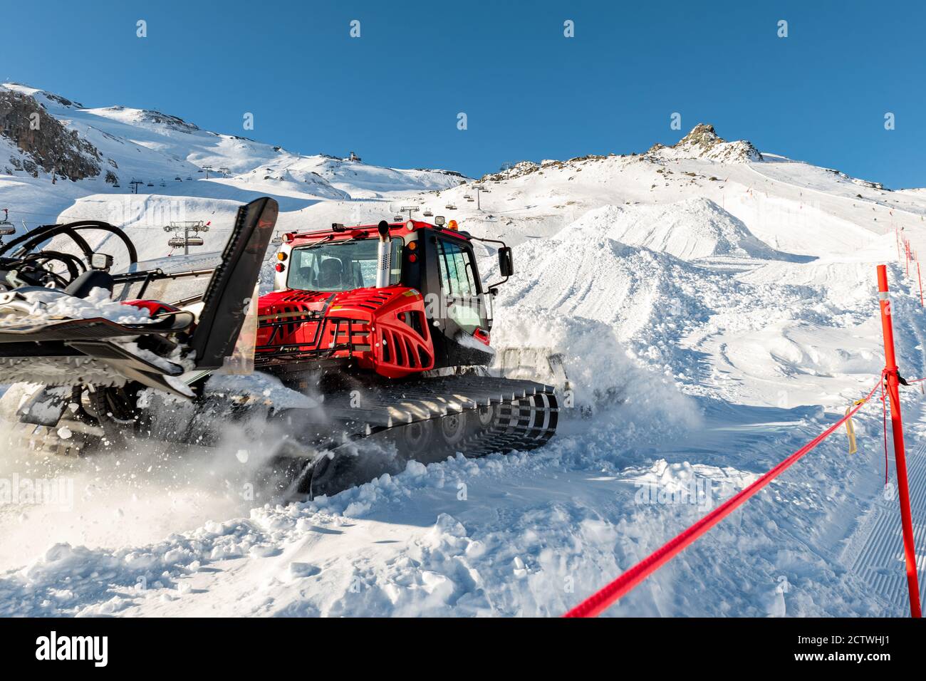 Red modern snowcat ratrack with snowplow snow grooming machine preparing ski slope piste hill at