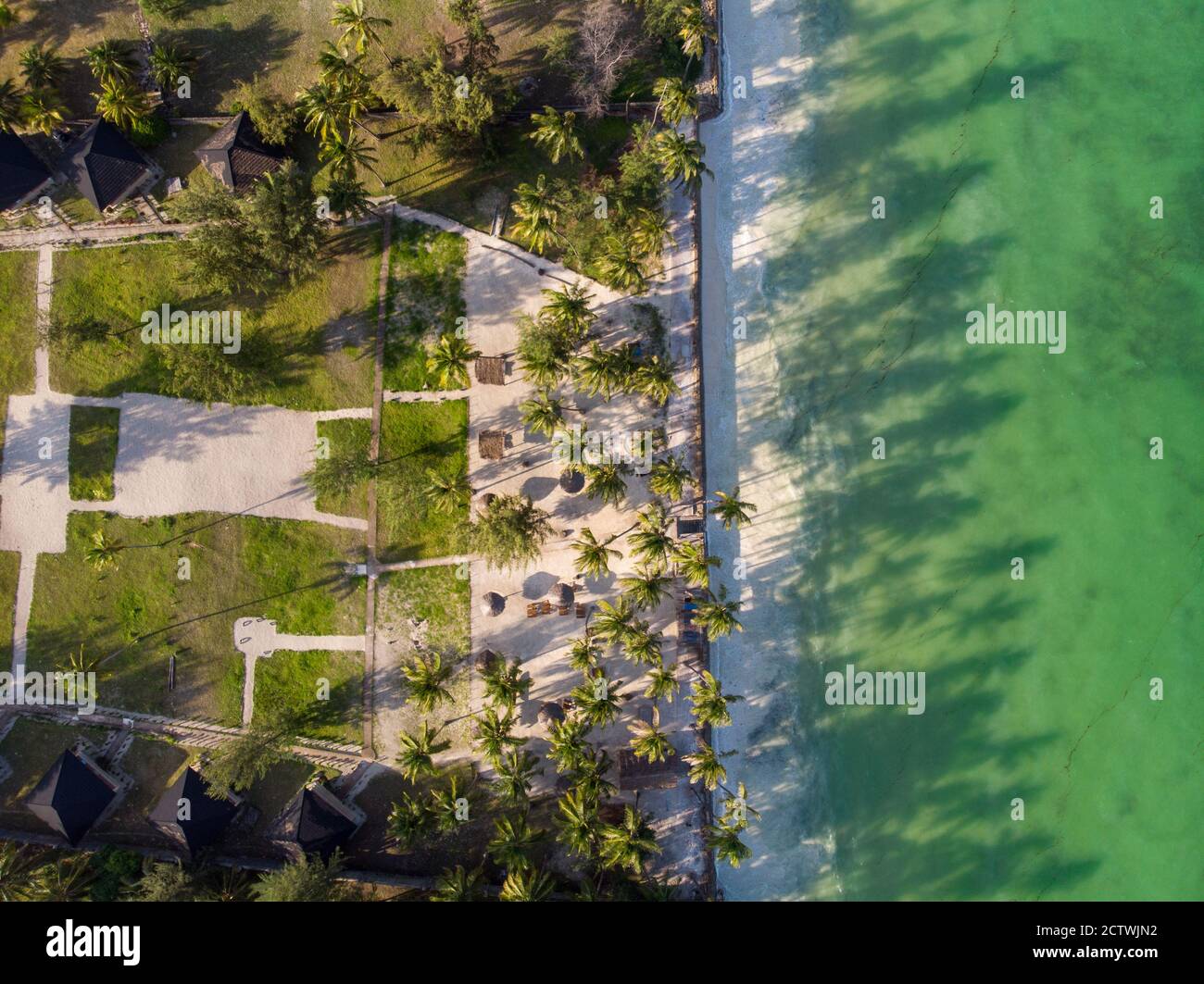 Aerial shot of a luxury hotel on a Beach first line with Palm Trees Drops their Shades on a High Tide Water of Indian Ocean at evening time in Paje Stock Photo