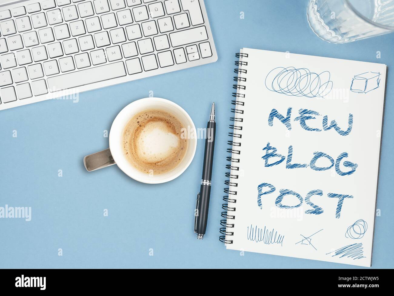 NEW BLOG POST scribbled on spiral notepad on blue desk with computer keyboard, blogging concept Stock Photo