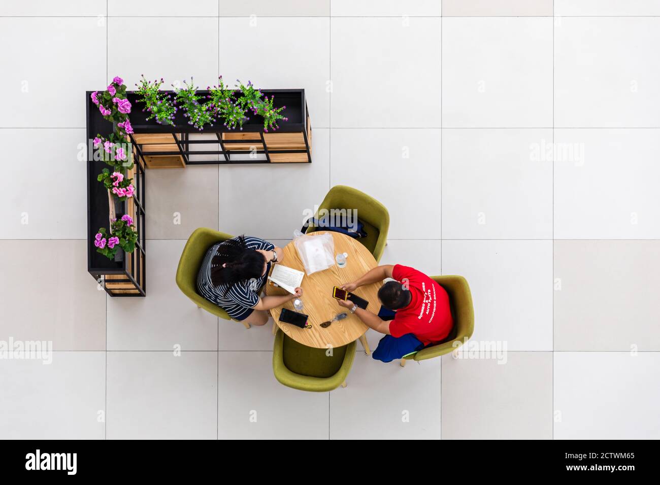Kota Kinabalu, Sabah, Malaysia: Interior of Sabah Regional Library at Tanjung Aru Plaza, 2 people readying and using smartphone. View from above. Stock Photo