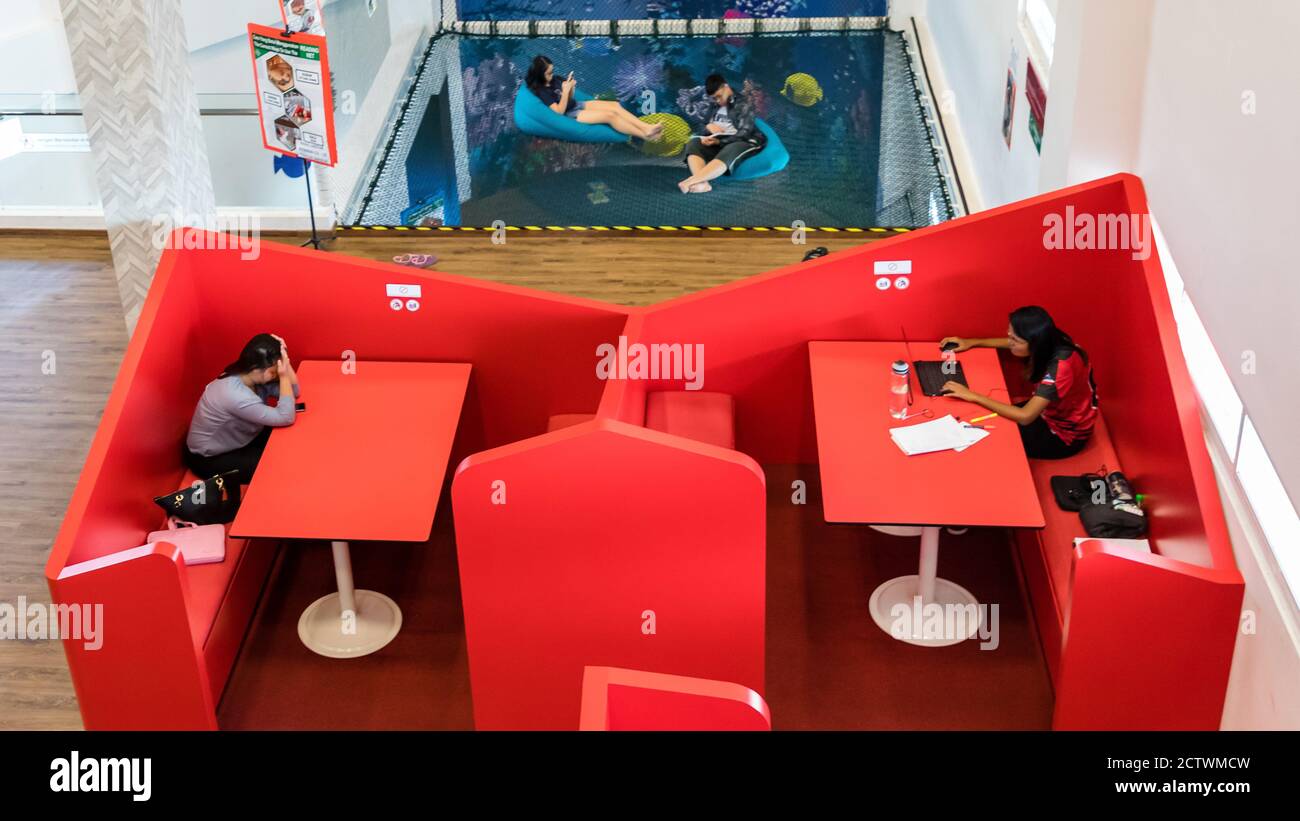 Kota Kinabalu, Sabah, Malaysia: Interior of Sabah Regional Library at Tanjung Aru Plaza with two studying people in the red seating corner Stock Photo