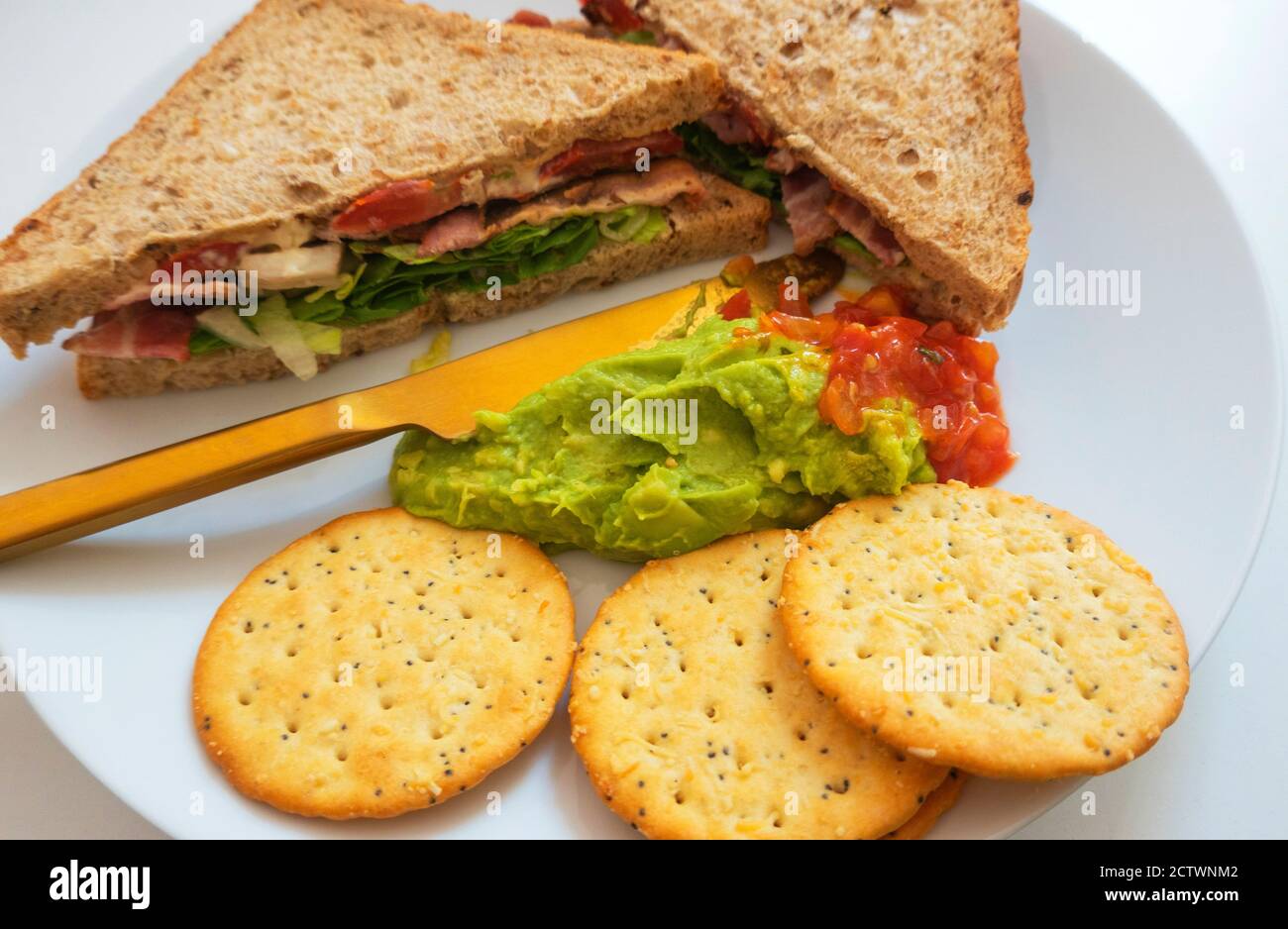 BLT, bacon, lettuce, and tomato sandwich on brown bread with guacamole and salsa and crackers Stock Photo