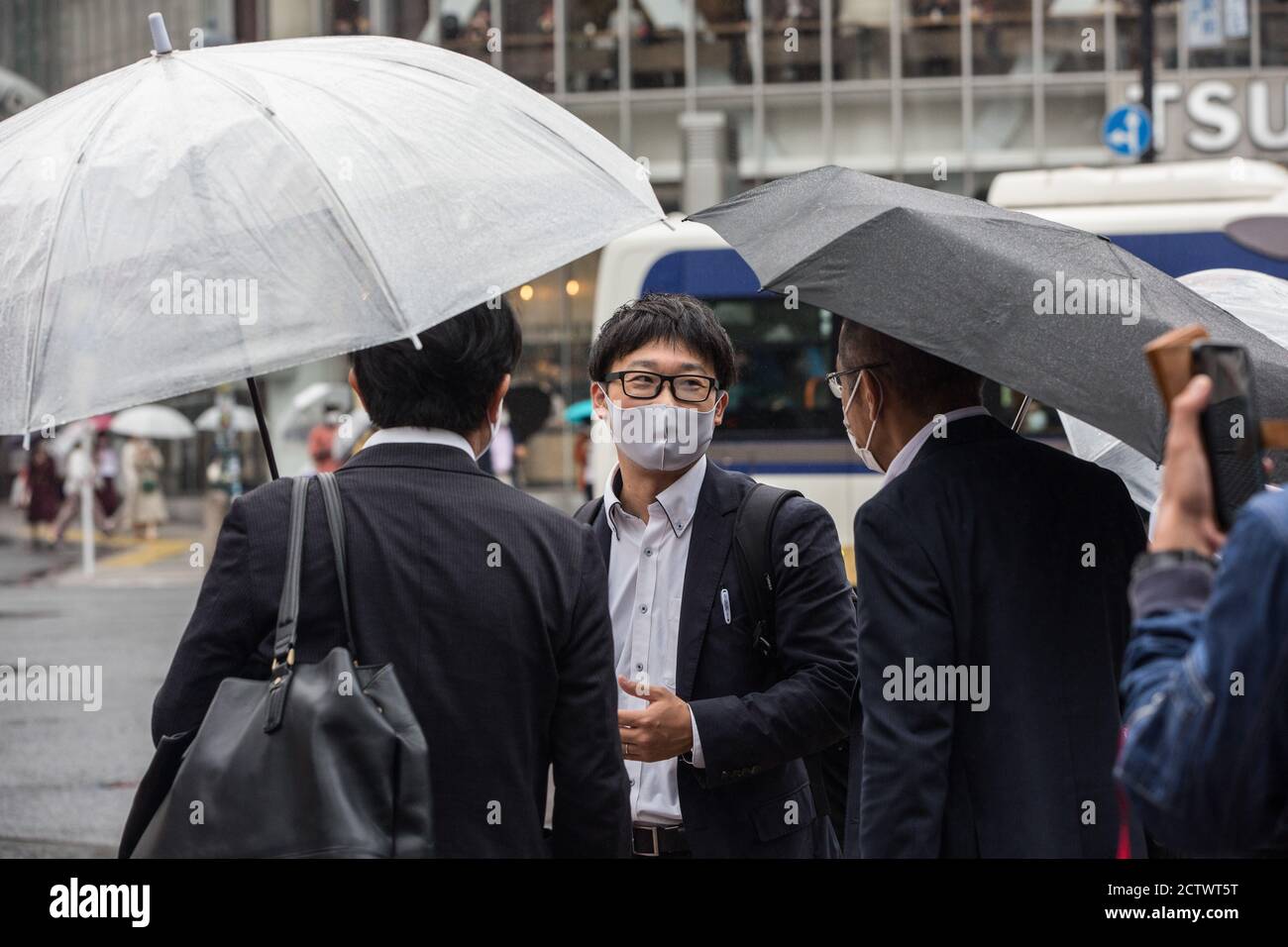 People holding umbrellas wait for a green light at the Shibuya Crossing ...