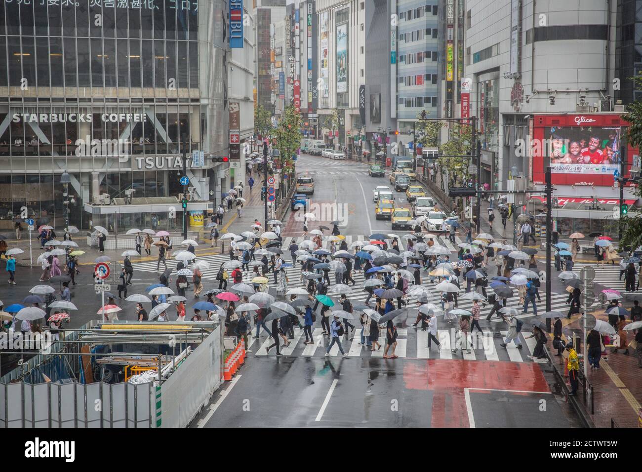 Pedestrians holding umbrellas cross the Shibuya Crossing during a rainy ...