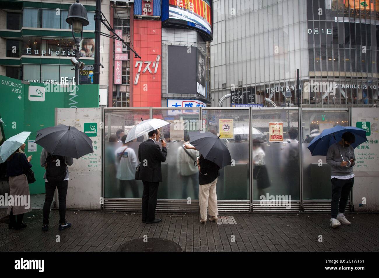 Smokers holding umbrellas at a designated smoking area near Shibuya