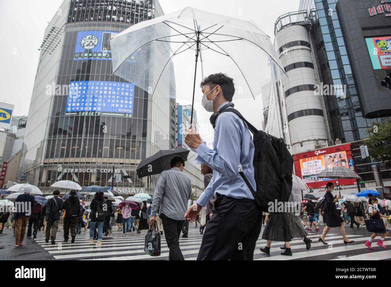 A man holding an umbrella crosses the Shibuya Crossing during a rainy ...
